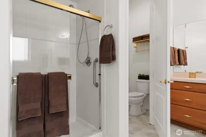 Nicely appointed primary bath with walk-in shower with built-in bench, and private water closet.