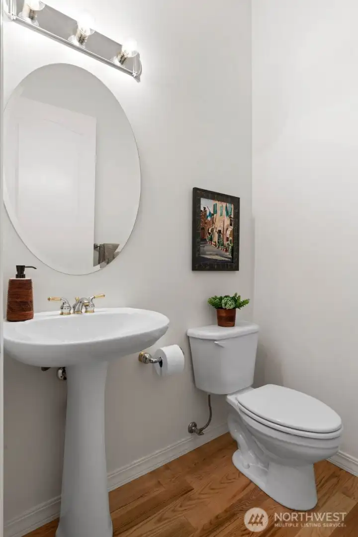 Conveniently located powder room, directly off entrance with warm hardwood flooring and pedestal sink.