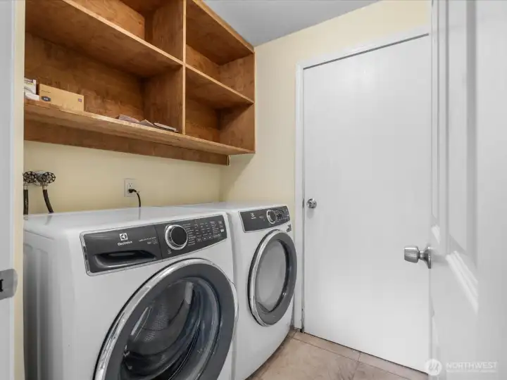 The laundry room has storage space and tiled floor.