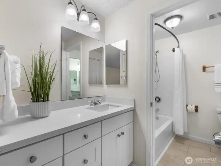 A door opens to the shared tub and toilet area.