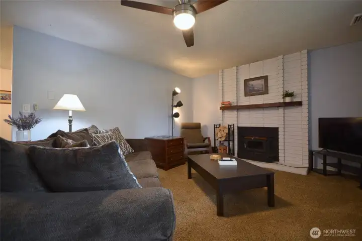 Step into this inviting living room featuring a charming brick fireplace with mantel and a wood-burning insert equipped with a blower—perfect for keeping you warm and cozy.