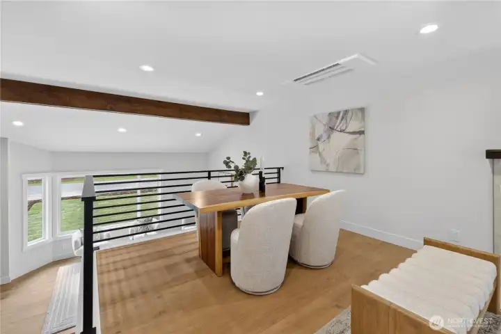 Set just above the front living room, the dining area enjoys a special sense of openness and connection. The custom linear handrail design accentuates the space, adding a clean modern architectural detail without closing off the view. Treetop views to both the front and back yards bring in natural light and a lovely outlook, creating a bright, inviting place to gather for meals and conversation. Set just above the front living room, the dining area enjoys a special sense of openness and connection. The custom linear handrail design accentuates the space, adding a clean modern architectural detail without closing off the view. Treetop views to both the front and back yards bring in natural light and a lovely outlook, creating a bright, inviting place to gather for meals and conversation.