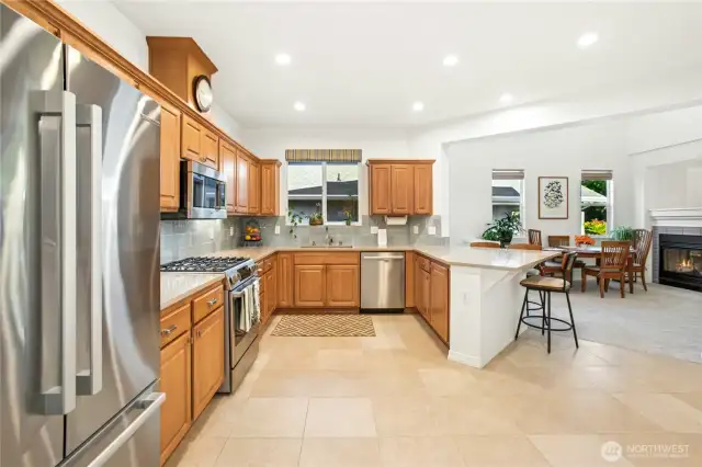 The fully upgraded kitchen features an oversized eating bar perfect for entertaining. Here you can see the gorgeous ceramic tile floors and gas cooktop