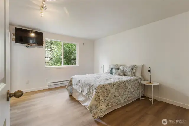Large primary suite features new luxury vinyl floors, green belt views, attached bath and large closet
