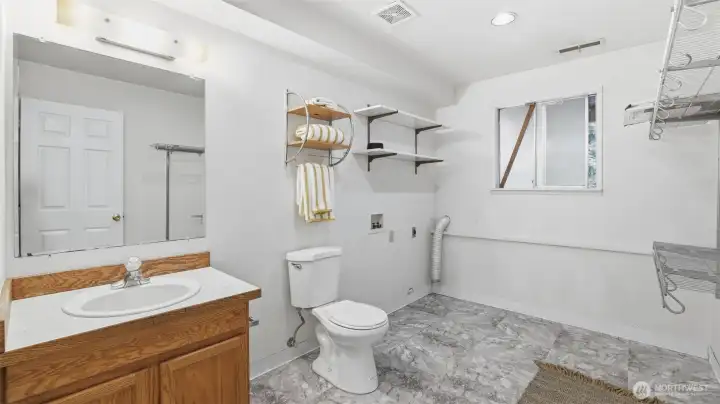 Convenient lower-level bath and laundry combo with room for storage and organization.