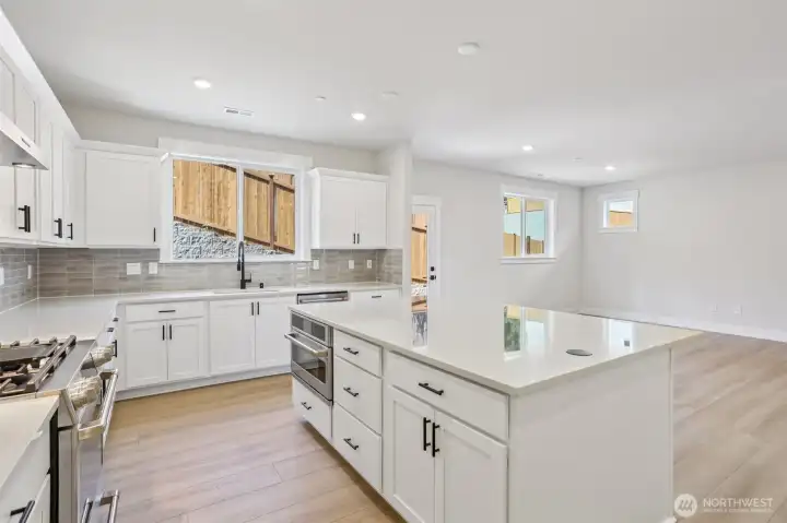 Ample working space is provided by the expansive kitchen island with microwave neatly tucked within.Photo is of similar home-details & finishes will vary-ask site agent for details