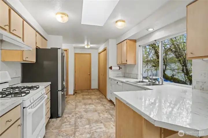 Kitchen view, plenty of counter space and I love the skylight and the large windows by the sink! Straight ahead to your right is your huge pantry, door to garage next to it for easy grocery commute!