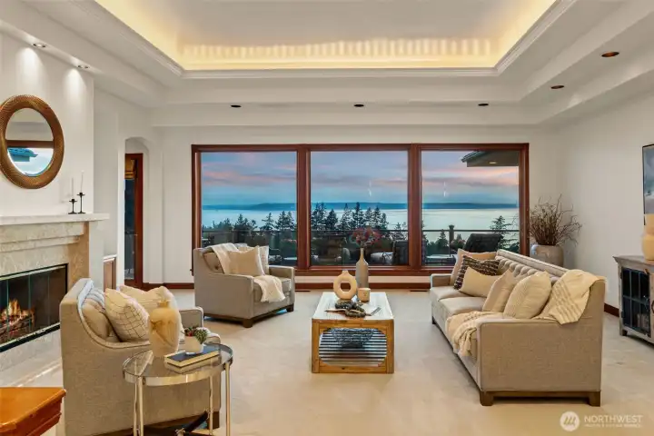 Elegant yet inviting, the formal living room was designed to showcase the home’s extraordinary Puget Sound and Olympic Mountain views. Expansive picture windows frame the ever-changing Northwest scenery while filling the space with natural light. A stunning fireplace, soaring tray ceilings with soft cove lighting, and beautifully crafted millwork create a warm, sophisticated atmosphere perfect for quiet evenings or gracious entertaining.