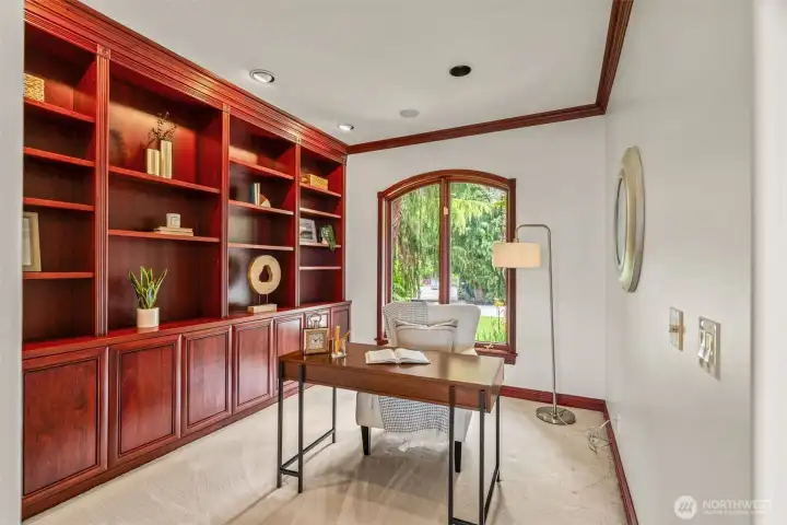 Thoughtfully designed for productivity and quiet retreat, the den features stunning custom built-ins, rich millwork, and beautifully crafted cabinetry that bring warmth and sophistication to the space. An arched window fills the room with natural light while creating a peaceful outlook, making this an ideal setting for a home office, library, or creative workspace. Elegant finishes and timeless design make this room both functional and inviting.