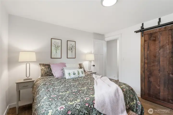 Inviting primary bedroom showcases beautiful barnwood-style sliding closet doors.