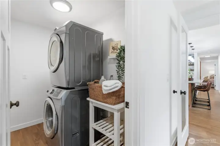 Practical laundry/utility room with bonus storage and neighboring built-in linen storage for added organization.