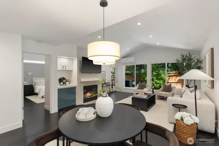 Soaring vaulted ceilings highlight the great room, complemented by ample recessed lighting, a wood-burning fireplace, a built-in bar area, and gleaming floors throughout.