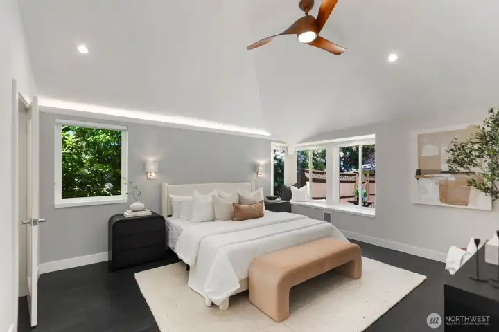 The spacious primary suite offers vaulted ceilings, a ceiling fan, a corner window seat, and specialty uplighting for a warm, inviting feel. A large walk-in closet and an upscale bathroom complete the space.