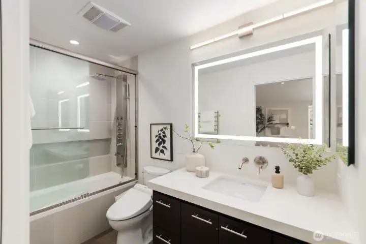 Primary en suite includes quartz counters, accent lighting, heated floors and towel rack, and an integrated shower head panel with multiple body sprays for a spa-inspired experience.