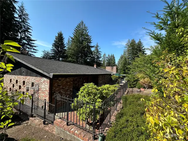 The vacant lot sits above the main house and is inclusive of mature trees, fruit trees, a fenced garden area and masonry storage shed.