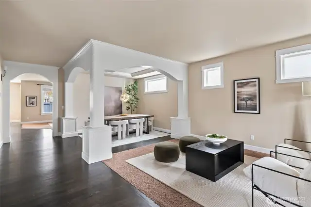 Open-concept formal dining and living areas with elegant hardwood flooring, millwork and arched transitions.
