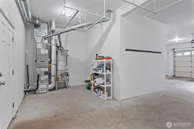3 car garage w/access to backyard features an additional utility space with recently serviced furnace, water heater, and additional shelving for storage.
