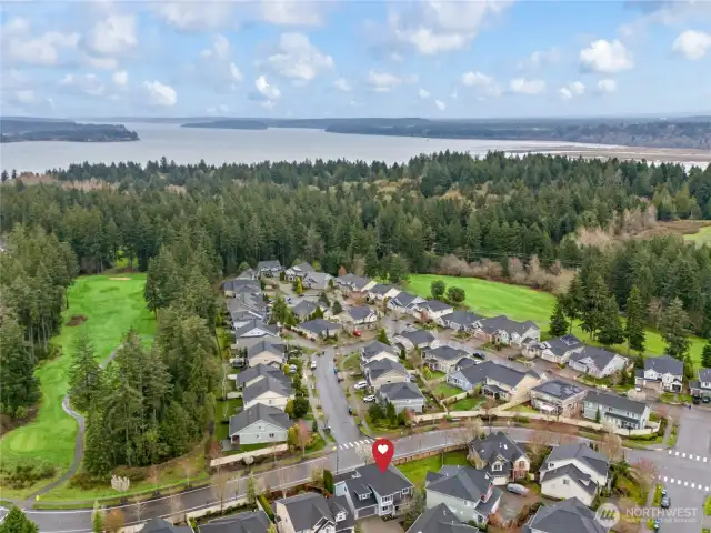 Bird’s-eye view of the neighborhood with the featured home highlighted — just minutes from golf, water access, and lush forested surroundings.