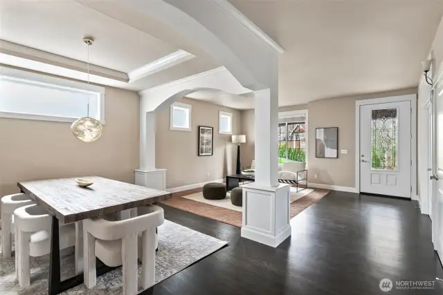 Elegant formal dining room with custom glass chandelier, coffered ceiling, architectural columns, and abundant natural light.