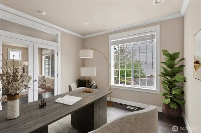 Private main floor office with French doors, crown molding and large window, perfect for remote work or study.  Photo virtually staged.