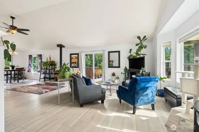 Walk in to an Open Concept Living Room with Big Bay Windows and a sliding glass door to the outside deck. Ceiling Fans and Wood Burning Fireplace for Seasonal Comfort