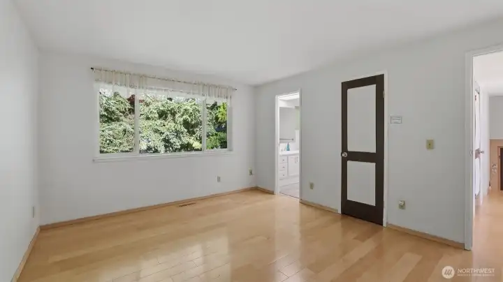 View of the primary without the virtual staging showcasing the gleaming floors and abundance of natural light.