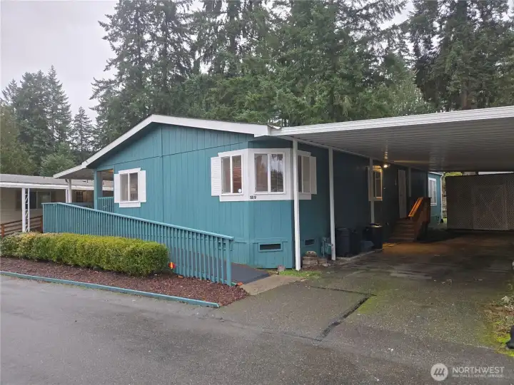 Front with carport and, in back, is large storage shed