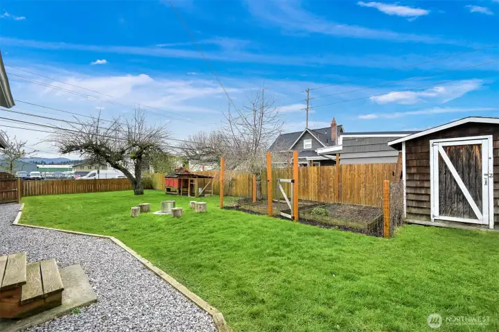 A storage shed, raised beds, fire pit, and chicken coop await you in this fully fenced side yard.