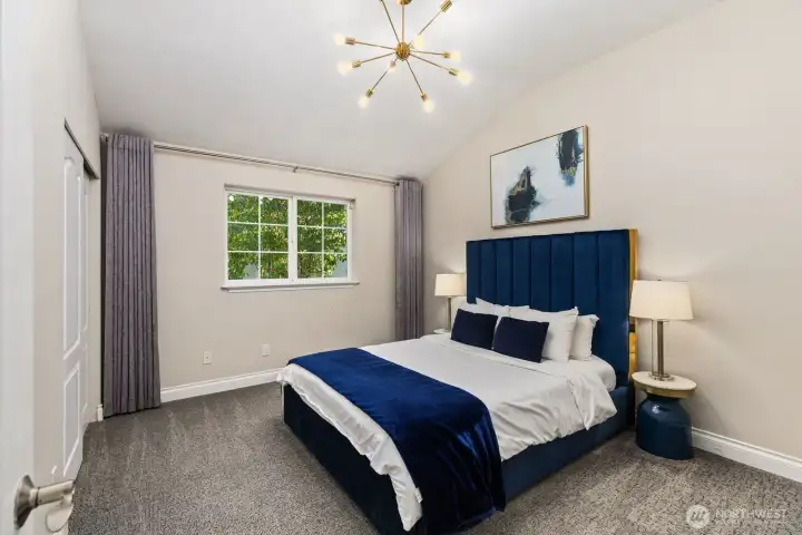 Elegant vaulted bedroom with designer lighting, plush carpeting, and a calming palette that exudes comfort and style.