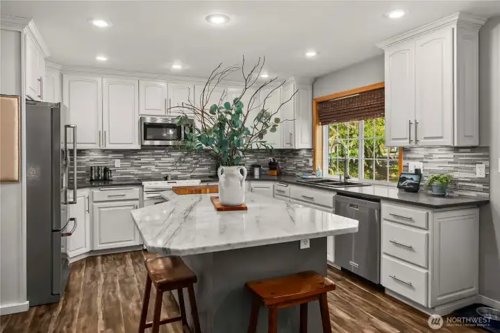 The custom island, topped with granite, offers outlets at each corner—ideal for meal prep, small appliances, and gathering space.