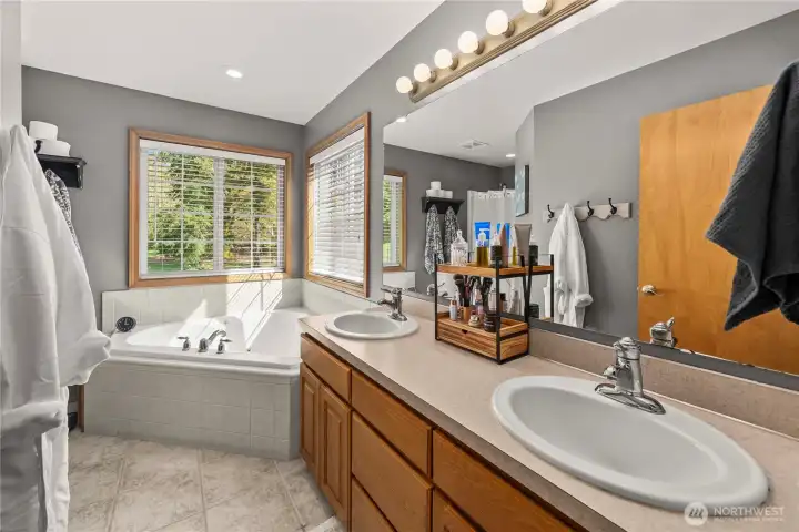 Primary bathroom with a corner tub and double vanities designed for comfort and convenience.