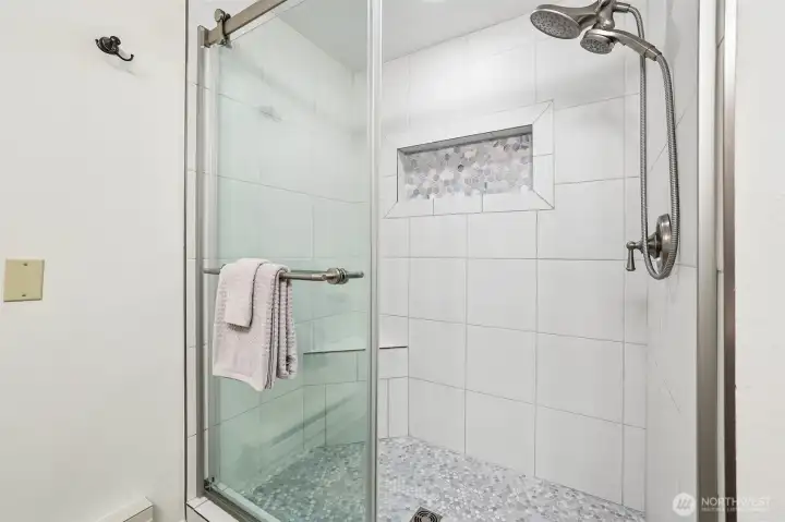 Glass enclosed tiled shower with light blues and whites Glass enclosed tiled shower with light blues and whites