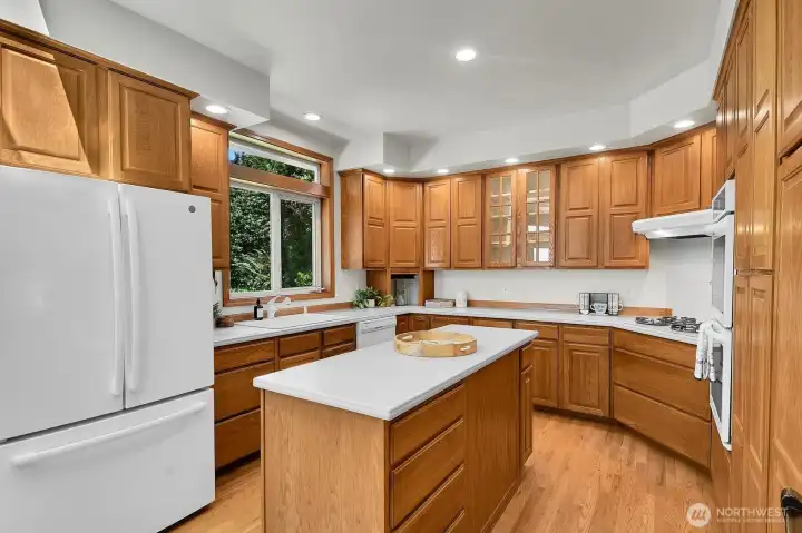 The kitchen offers abundant cabinetry, generous counter space, a center island, and hardwood floors.