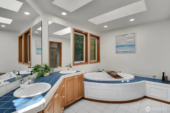 The primary bath features dual vanities, a soaking tub, and abundant natural light from the skylights.
