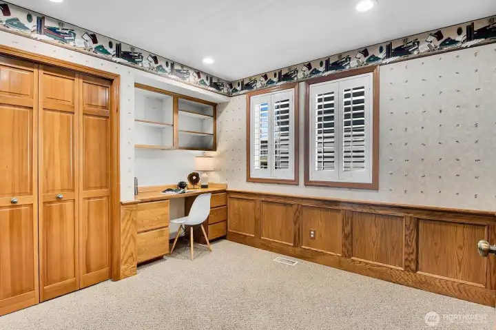 A versatile 3rd bedroom or office featuring built-in desk space, oak wainscoting, and plantation shutters. This room has direct access to the guest bath.