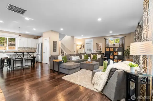 From the sleek recessed lighting to the richly toned floors, this living space delivers on design. The layout flows right into the kitchen, where a pantry closet offers bonus storage next to the fridge. With the staircase leading up and the exterior door inviting you out, every turn feels purposeful and polished.