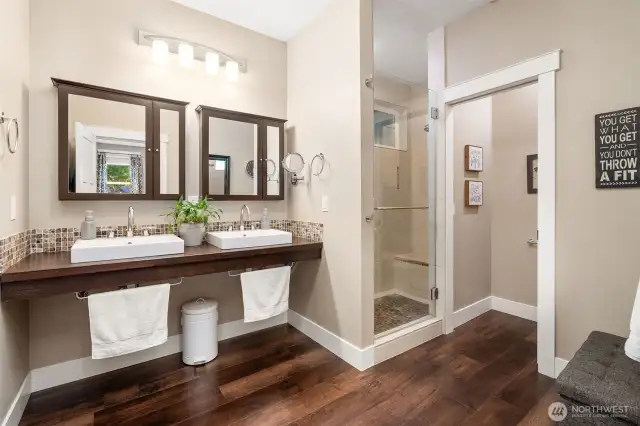 Step into a bathroom that’s all about clean lines and smart design. Suspended double sinks create a floating effect, paired with modern mirrors that hide built-in medicine cabinets for a clutter-free look. The glass-door shower lets in natural light from the upper window, while the separate toilet closet keeps privacy on point.