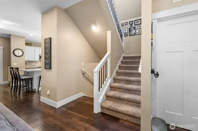 The staircase blends style and function with carpeted steps that soften every footfall. Crisp white banisters pair effortlessly with black metal spindles for a look that’s modern yet classic. Positioned just off the kitchen and entry, it’s a smooth transition between spaces that feels intentional and inviting.