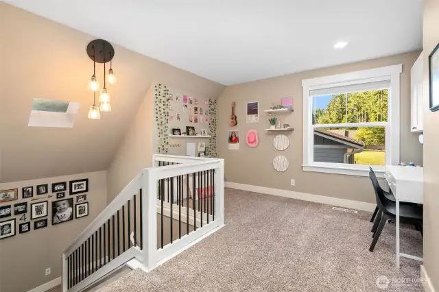 At the top of the stairs, this loft offers a bright, flexible space perfect for an office, homework zone, or quiet retreat. The large window overlooks the front lawn and driveway, letting in plenty of natural light. Warm oatmeal carpeting keeps things cozy, while the skylight above the staircase adds a fresh, airy touch.