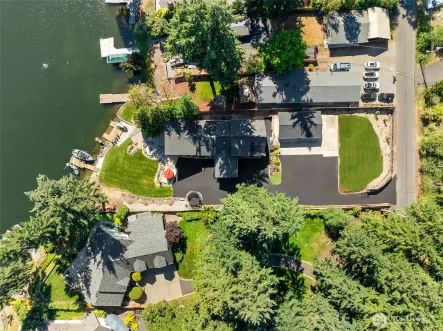 This top-down view shows off the serious layout planning. The 4-car garage sits just steps from the home, the driveway is freshly paved and wide enough for trucks, guests, and maybe even a casual pickleball court, and the lawn rolls gently toward two private docks. Long Lake allows motorized boats from 11 to dusk, which means you get glassy morning paddles and action-packed afternoons without sacrificing the quiet vibe.