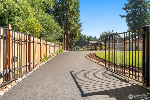 Gated, landscaped, and laid out to impress. The entry leads to a sleek new asphalt drive with neat borders of river rock and bark that guide the eye toward a house that knows how to make an entrance. There’s no shortage of lawn for games, gardens, or a summer soirée, and the overall feel is crisp, private, and totally ready for your arrival.