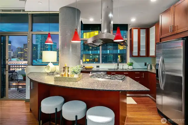 Open kitchen with breakfast bar, natural gas cooktop, and all KitchenAid stainless steel appliances.