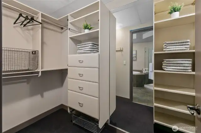 Large walk-in closet with built in closet system and floor-to-ceiling mirror.