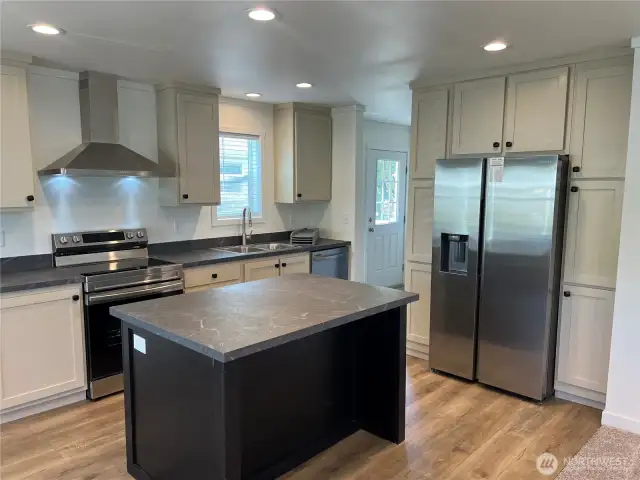 Kitchen with pantry, island and stainless Samsung appliances.