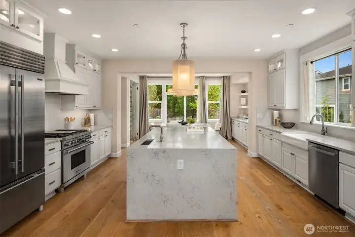 The dream kitchen boasts a dramatic waterfall island, Wolf appliances, a Sub-Zero refrigerator, upgraded  cabinetry, a butler’s pantry, and more!