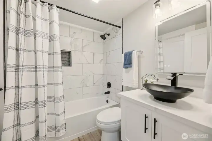 Full bath on the second floor with custom tile surround and built in cubby.