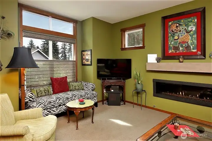 Living room fireplace in wall, with forged metal frame, lighted glass bed and custom Traverstone mantel.
