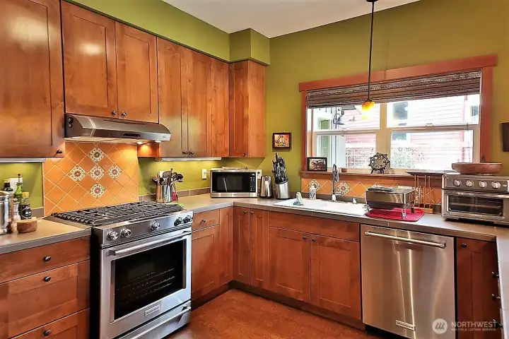 Counter tops are large tile format in taupe throughout. Stainless steel appliances -- Kitchen Aide refrigerator, new LG stove, Broan venting.  Mexican orange tile back splashes throughout kitchen.