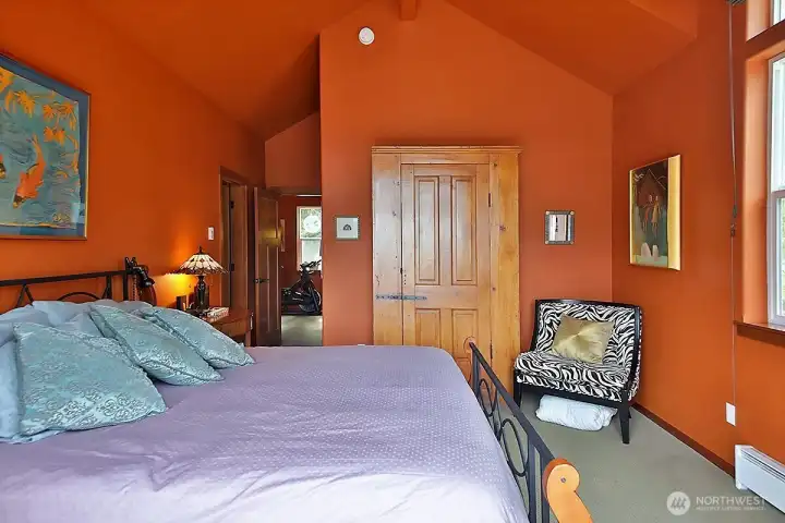 Primary bedroom with vaulted ceilings, transom windows and French doors to upper deck.  Baseboard heater is "Soft Heat" in addition to ductless mini split.