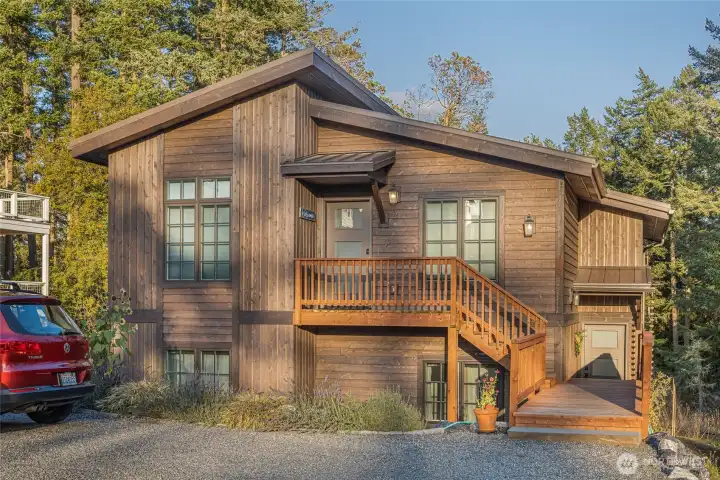Front exterior highlighting the home’s modern Northwest architecture, warm wood siding, and private upper-level entry, blending beautifully with the natural island surroundings.